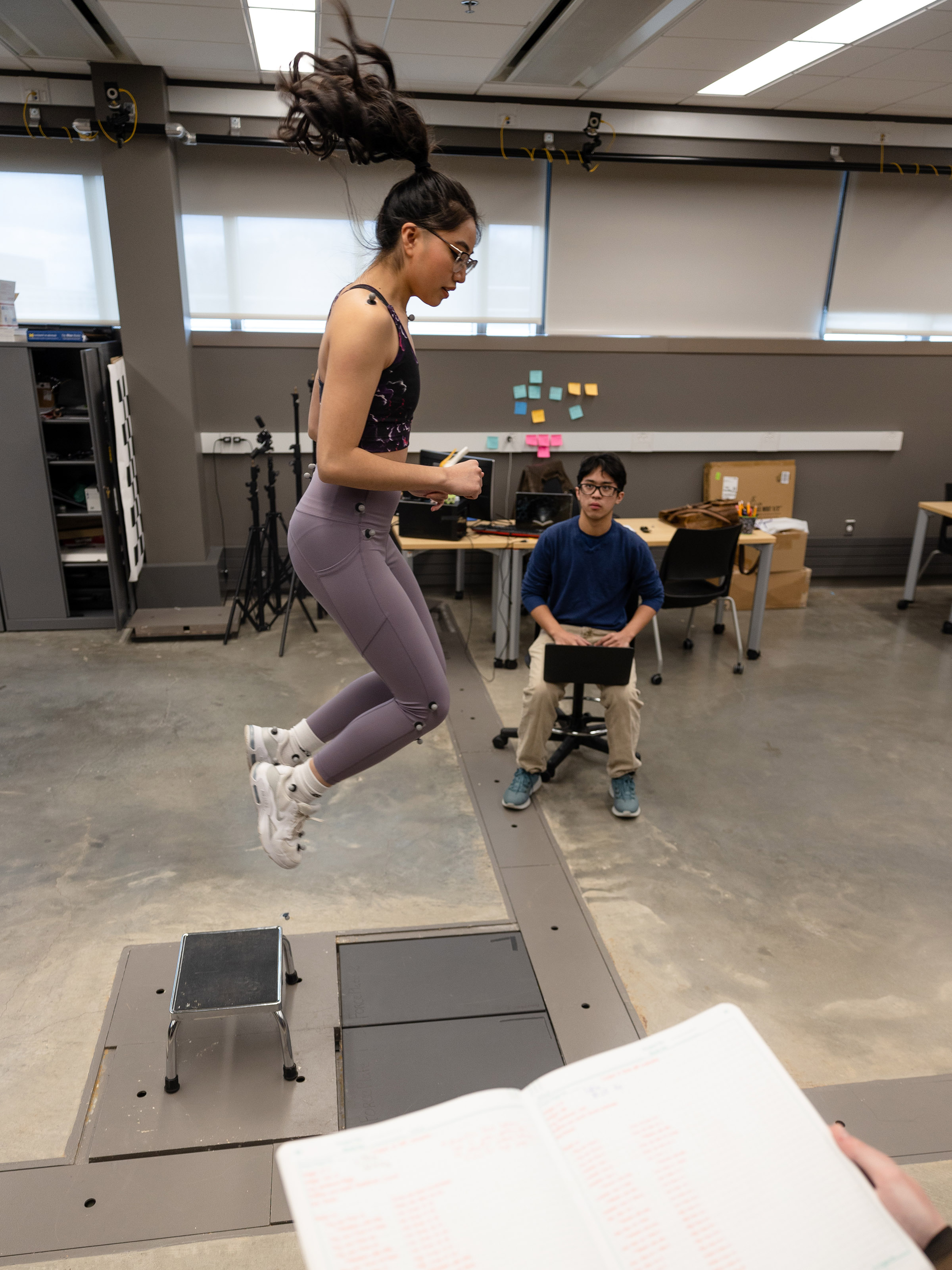A student wearing wearable sensors jumps high into the air off a platform to measure the force of impact in Professor Amanda Esquivel's bioengineering lab.