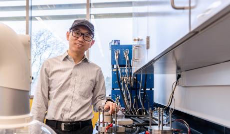 Surrounded by lab equipment, Associate Professor Xuan Zhou poses for a portrait in his UM-Dearborn battery lab.