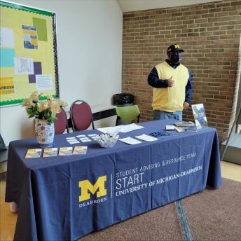 academic advisor standing behind a table with fliers on table