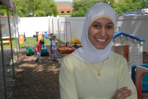 Female student in hijab standing in front of playground