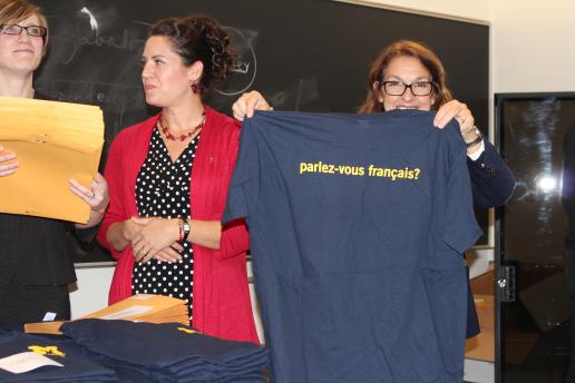 Women holding up blue t-shirt which reads: parlez-vous francais?