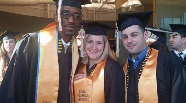3 students pose in the graduation attire.