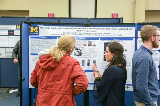 Student sharing research in front of her poster.