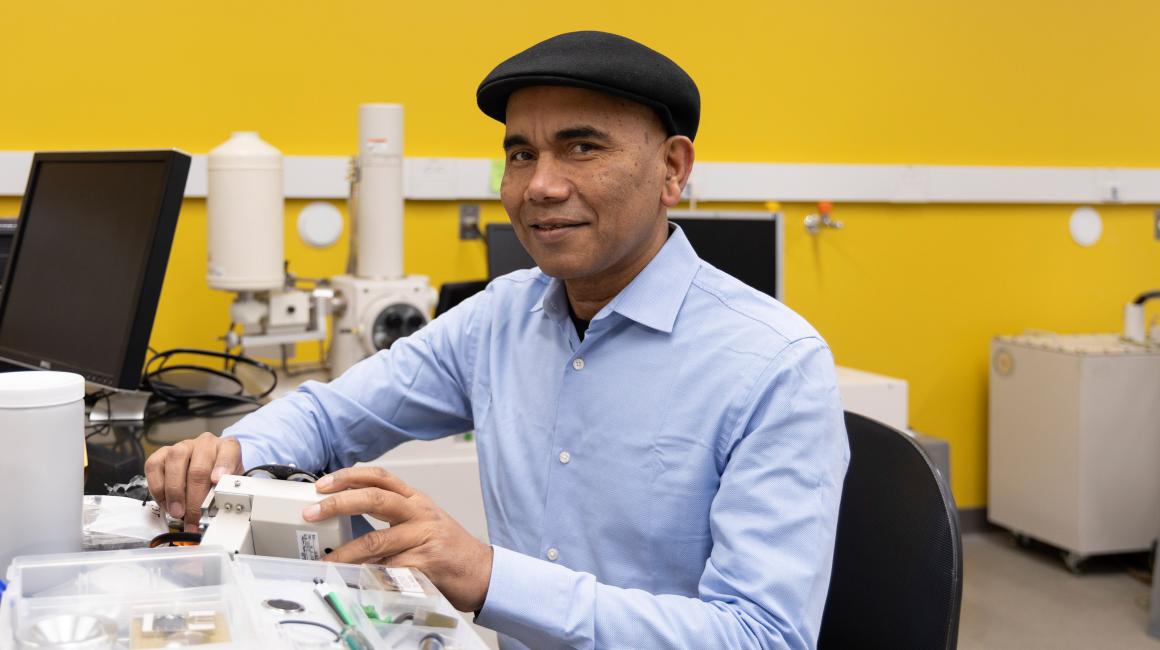 Wearing his signature black flat cap, UM-Dearborn Professor Pravansu Mohanty sits for a portrait in his UM-Dearborn mechanical engineering lab
