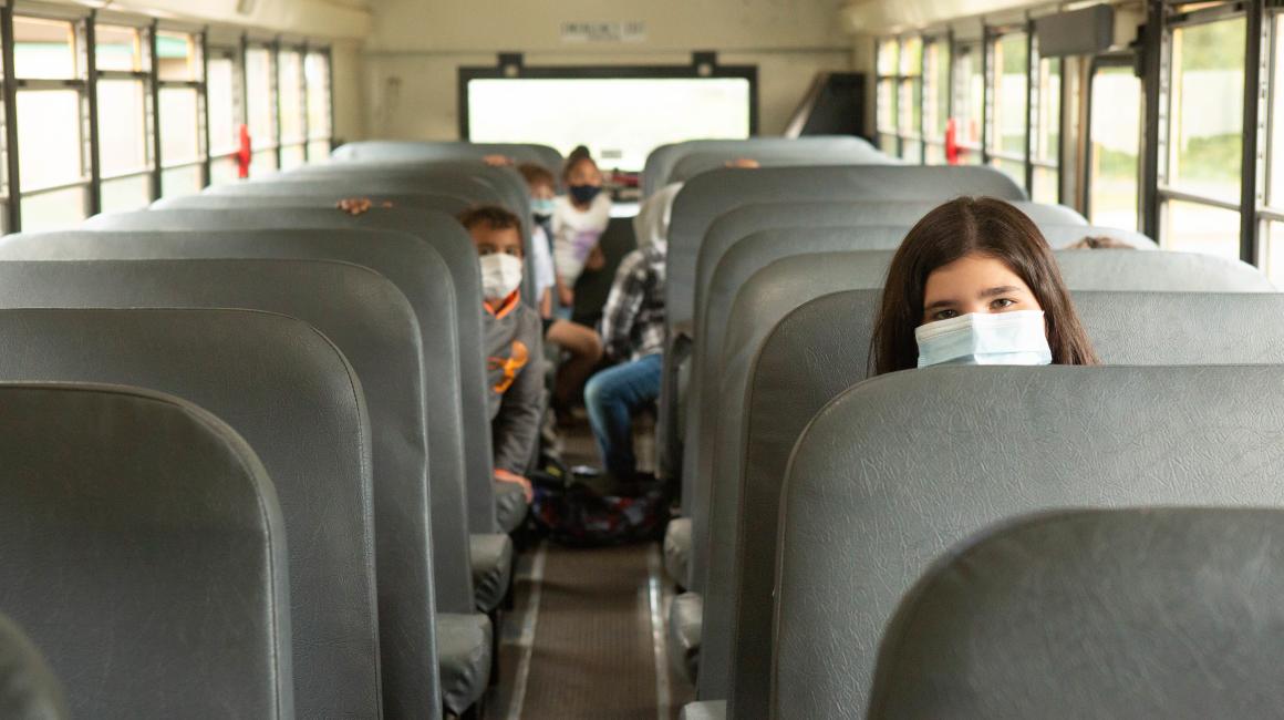 A group of children wearing face masks on a school bus.