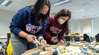 Two members of a sorority cut fabric to make blankets during the UM-Dearborn MLK Day of Service in 2022