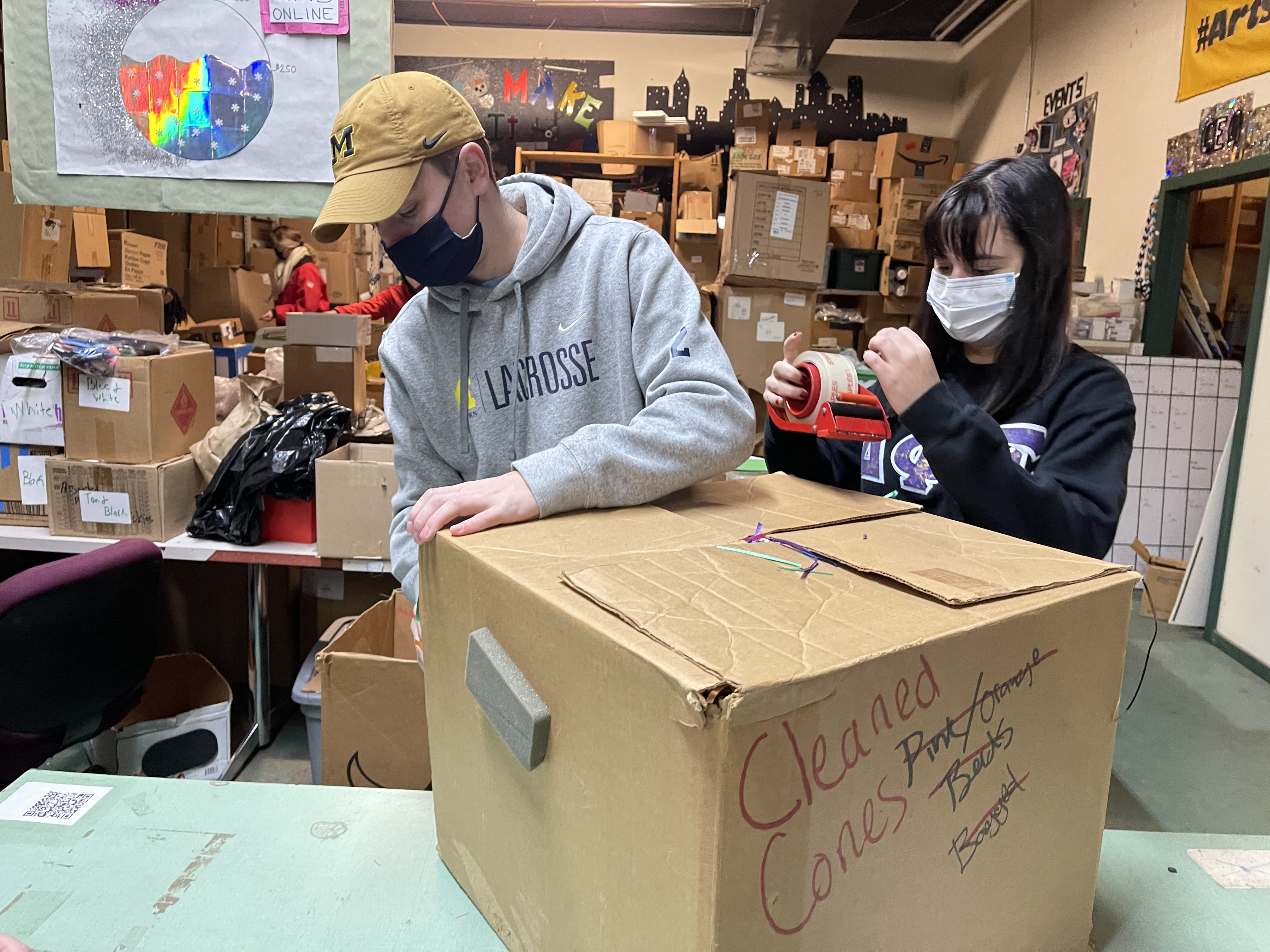 Photo of UM-Dearborn students Jack Meyers and Allyssa Decato sorting boxes of supplies at Arts & Scraps in Detroit