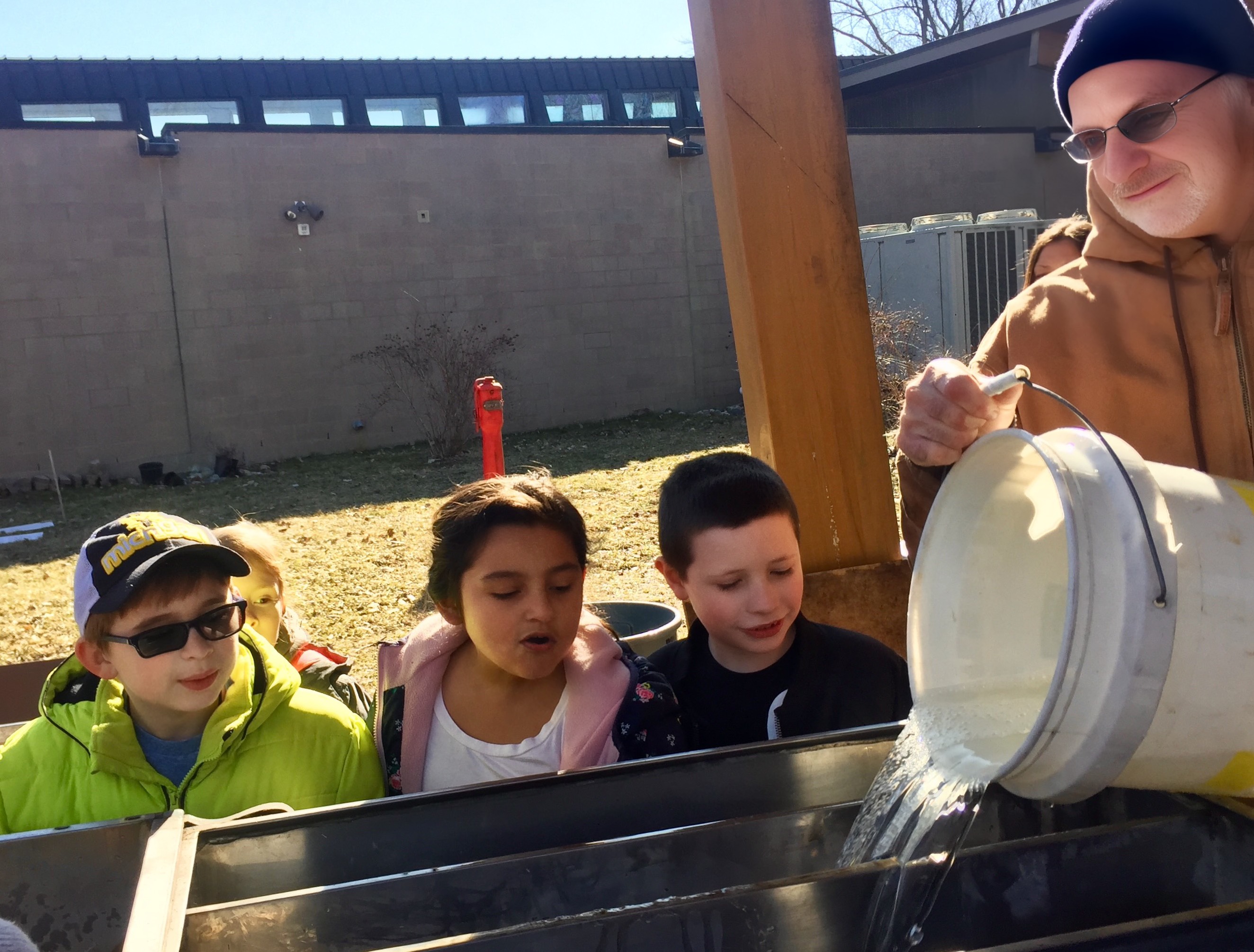 EIC staff member Rick Simek pours sap into the outdoor maple syrup kitchen