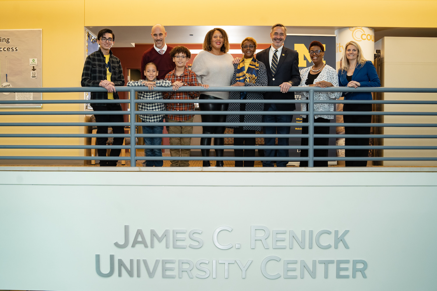 People in the UM-Dearborn gather on the balcony of the University Center over the new name plate celebrating James C. Renick