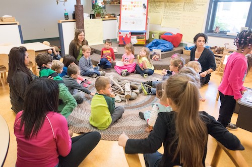 Teachers and young students sitting in a circle.