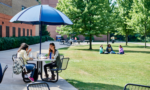  Students studying at a table outside the University Center on a late summer day. 