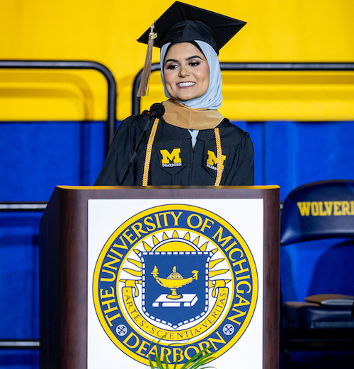 Graduating student standing at podium delivering commencement remarks