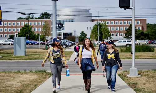 Three students walking across campus.