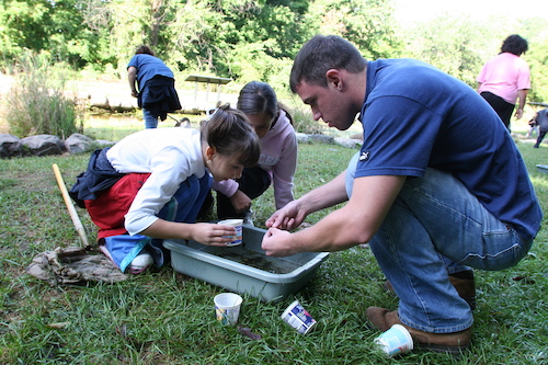 Two students and adult are exploring the pond