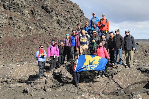 Group of students pose on mountain with UM-Dearborn flag