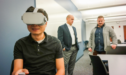  UM-Dearborn faculty Feng Zhou (foreground) and David Hill (center) and UM-Flint’s Benjamin Emihovich try out a demo of their new MCubed virtual reality project. 