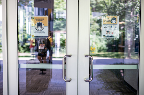  Photo of Natural Science Building doors with face covering required signs. 
