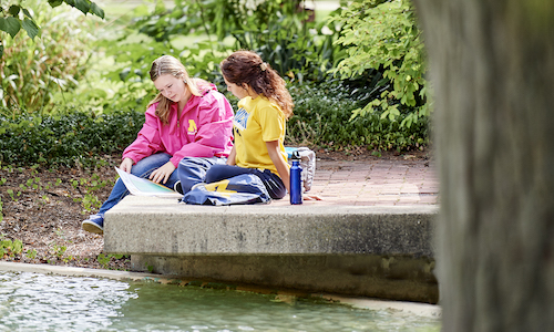 Two students sitting by the Chancellor's Pond