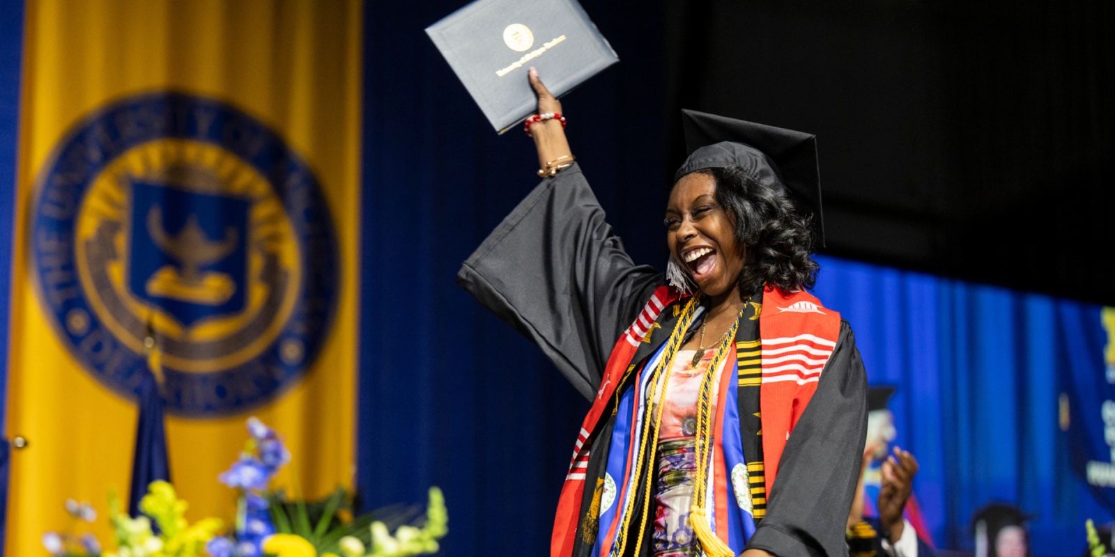 A UM-Dearborn graduate walks across the stage at the Spring 2024 commencement ceremony.