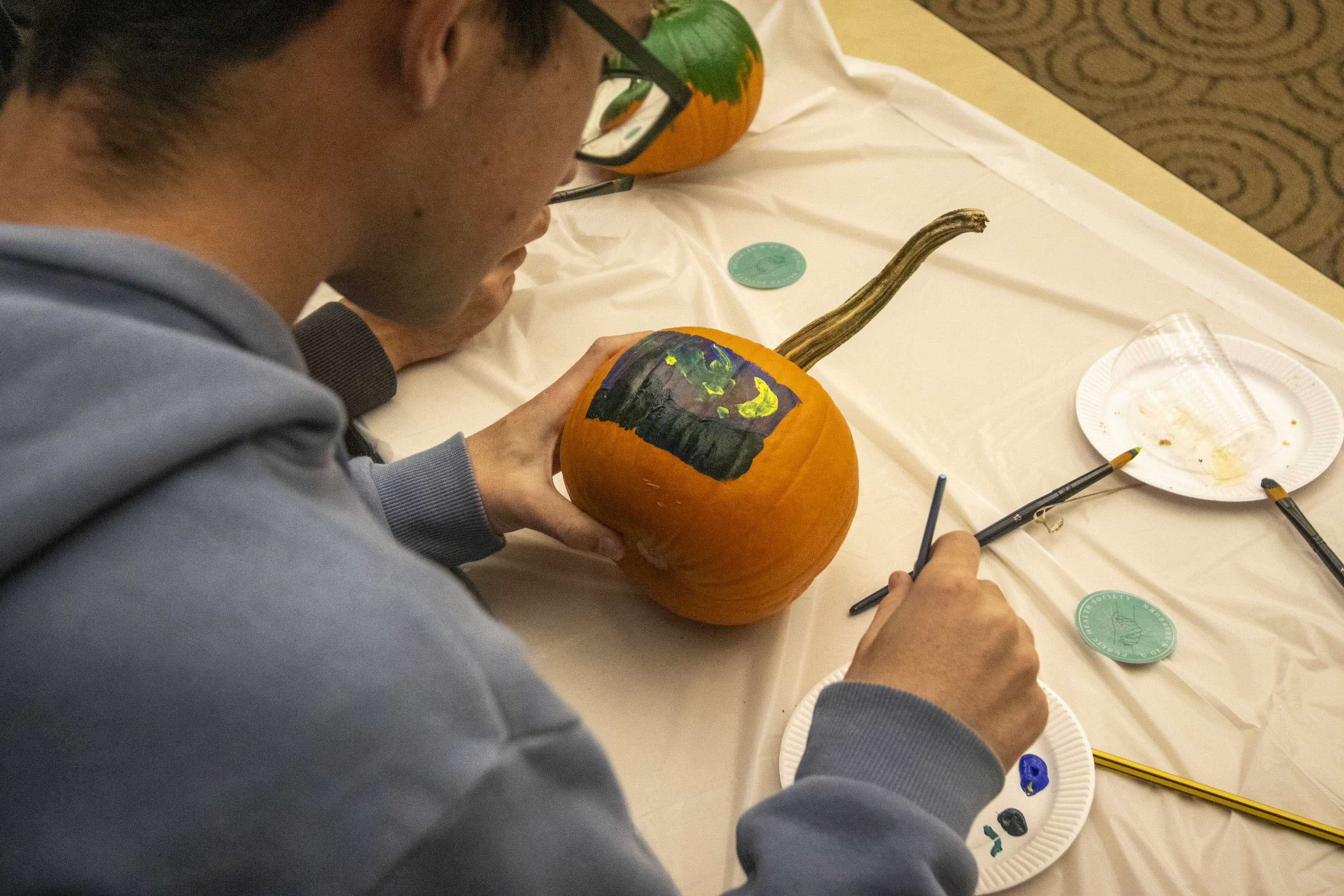 A student paints a pumpkin during a 2024 Halloween event