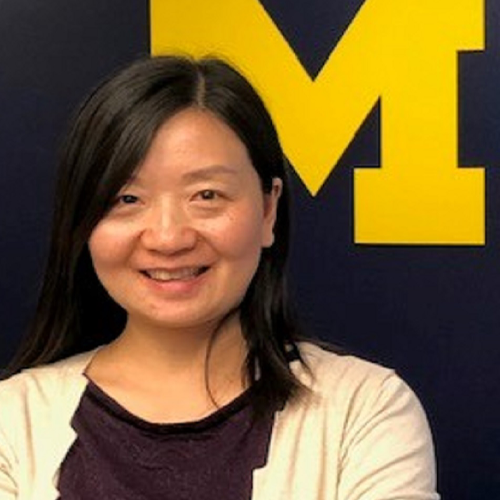 Person smiling in front of a University of Michigan logo.