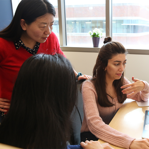 Four people engaged in a discussion around a table in an office setting.