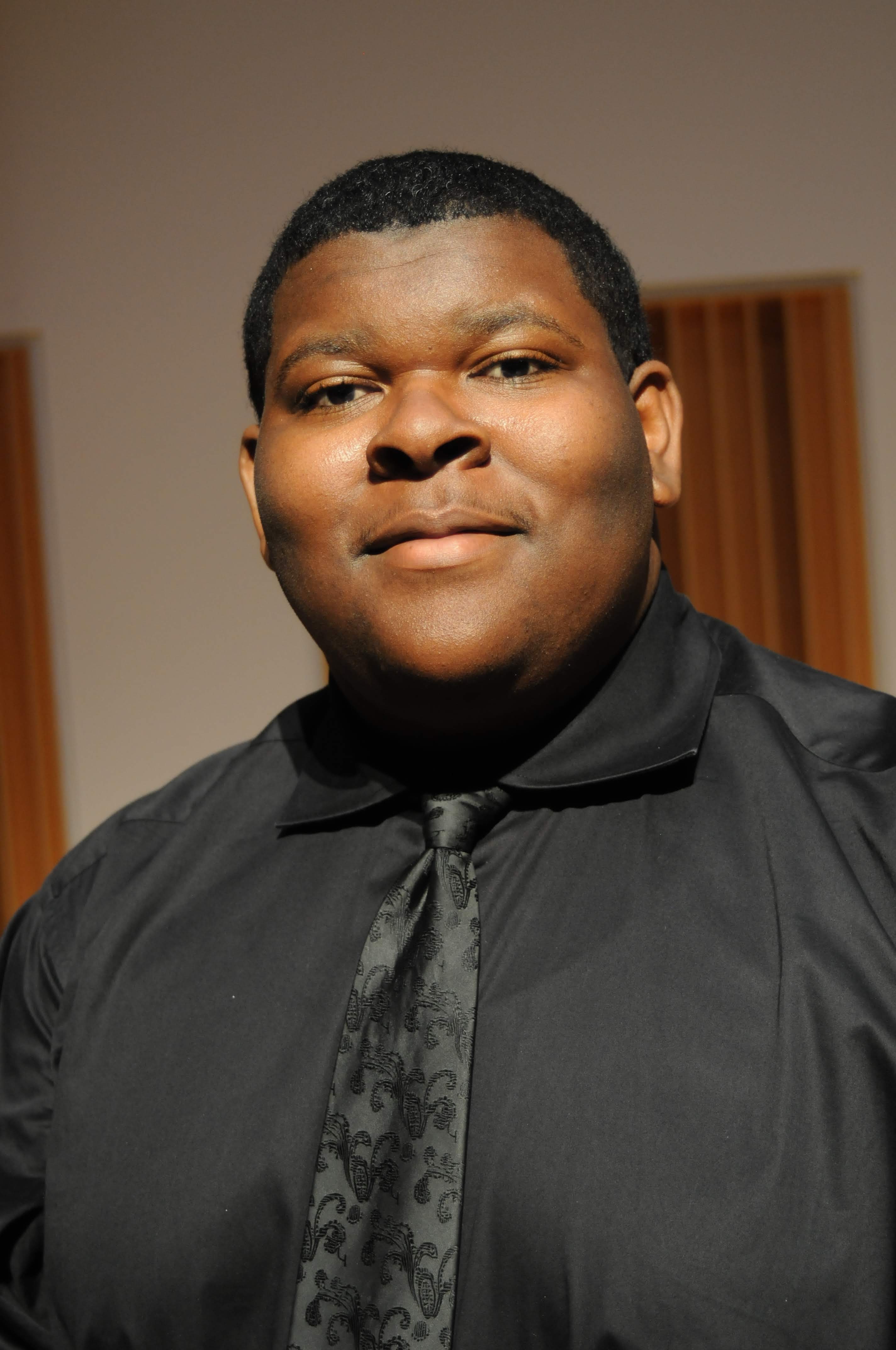 A photo of Dennis Brown in a black shirt and tie