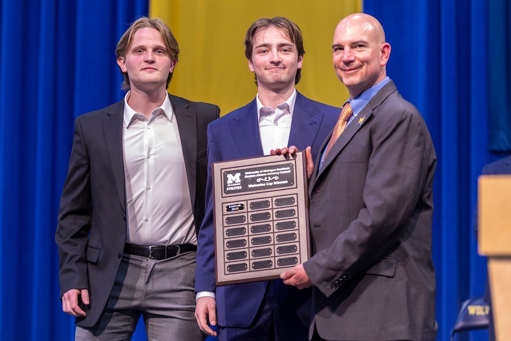 Two students are handed an award from the UM-Dearborn athletic director.
