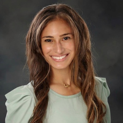 A smiling woman with long brown hair is wearing a light green top