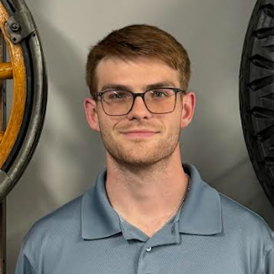 A man wearing glasses has on a gray-blue collared shirt