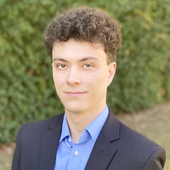 A man wears a blue suit over a collared-blue shirt