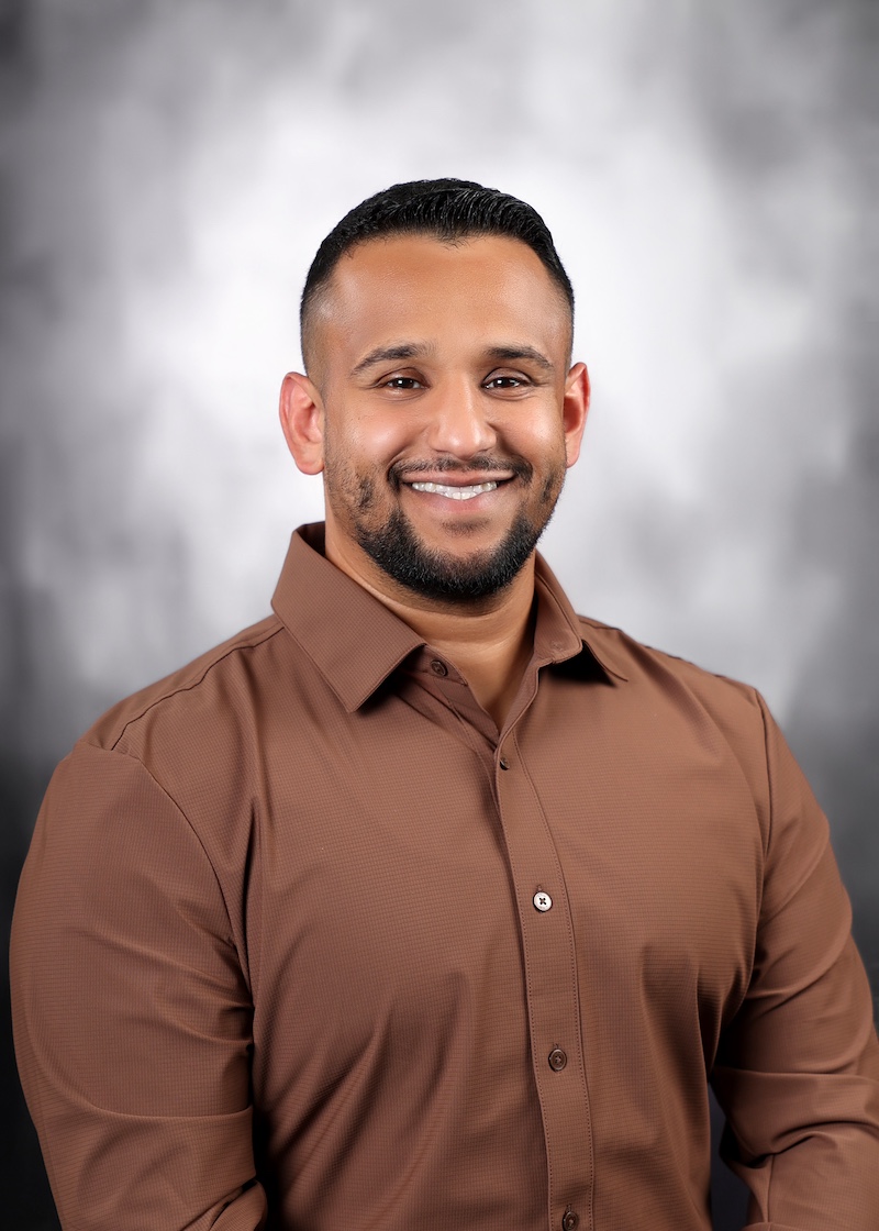 Hussain Alburkat, a smiling man in a tan shirt