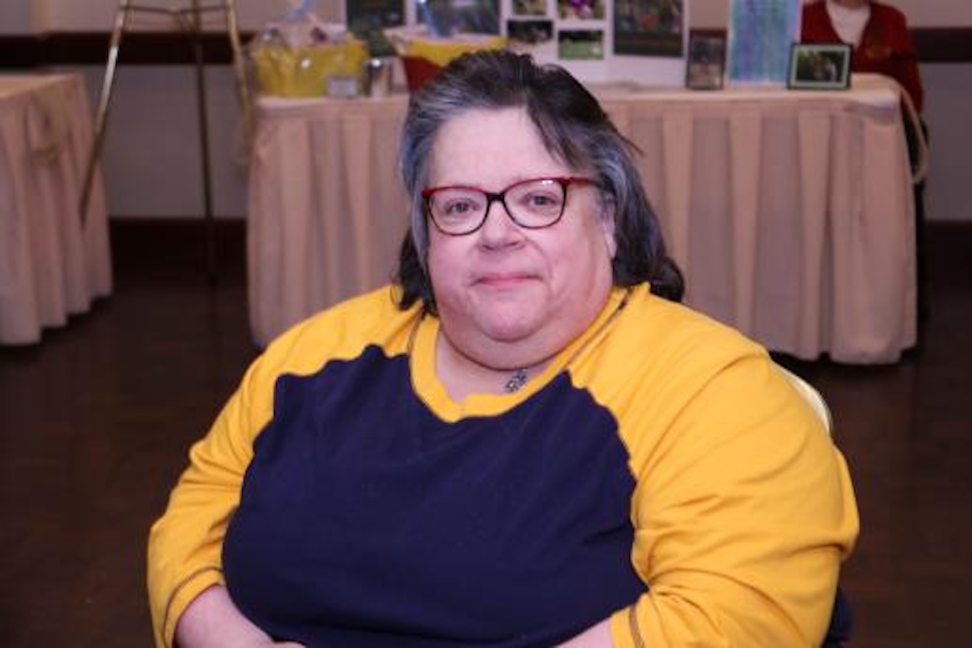 A photo of a woman who is wearing a blue shirt with yellow sleeves