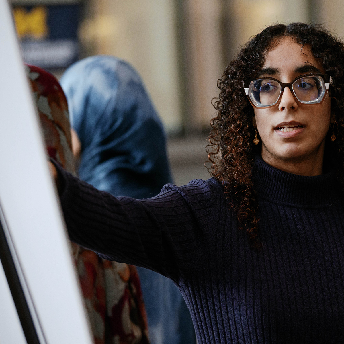 Person pointing at a poster board in a professional setting.