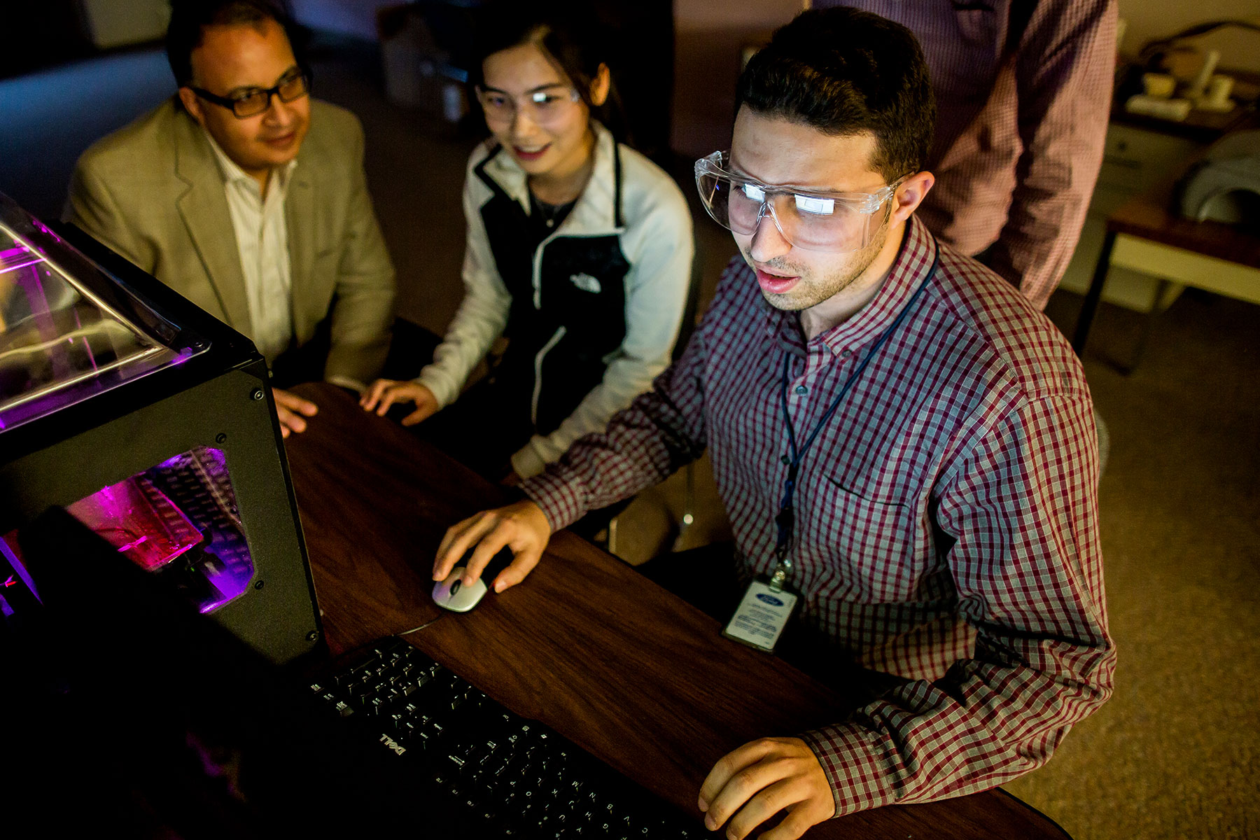 Student programming a 3D printer on a computer surrounded by peers