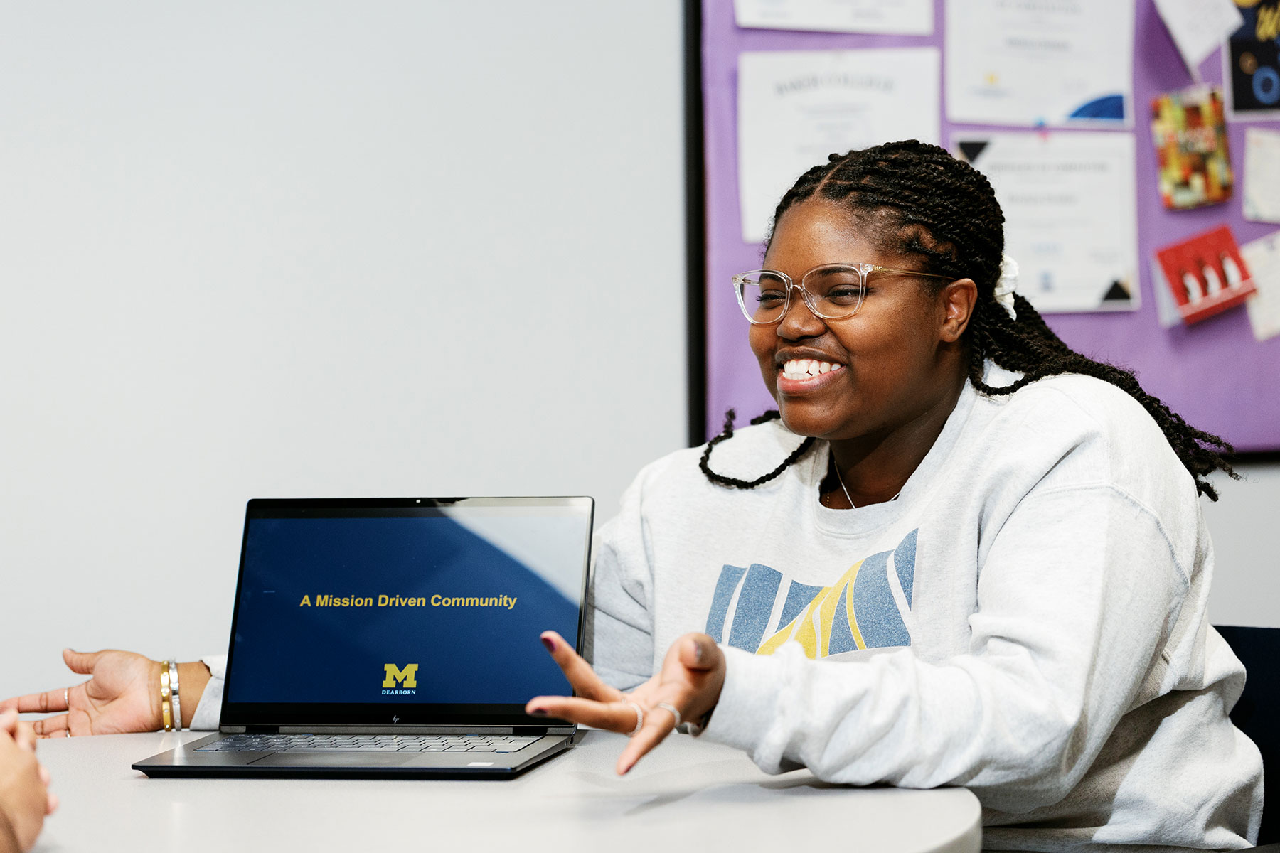 UM-Dearborn student Kalaia Jackson smiling at a table with a laptop