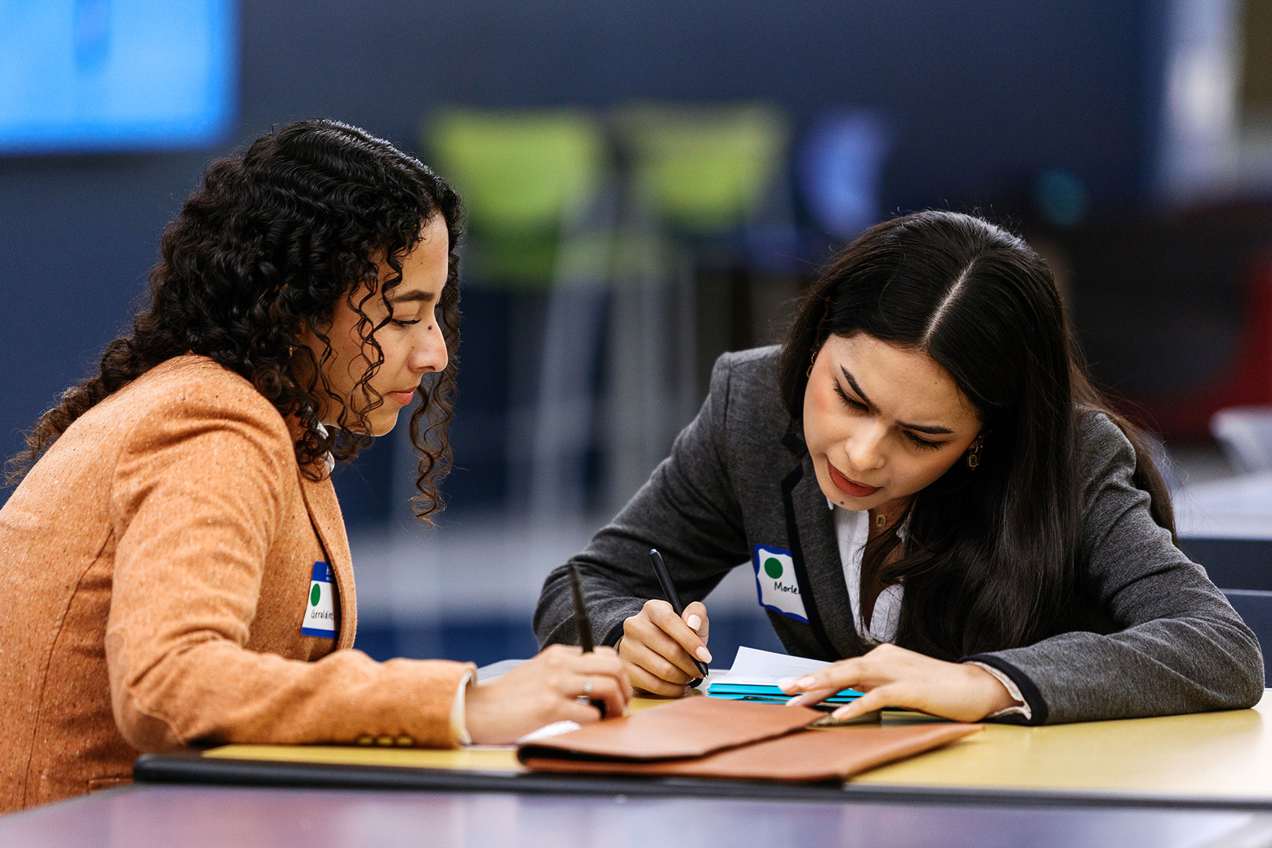 Two UM-Dearborn students taking notes intently at a career fair on campus