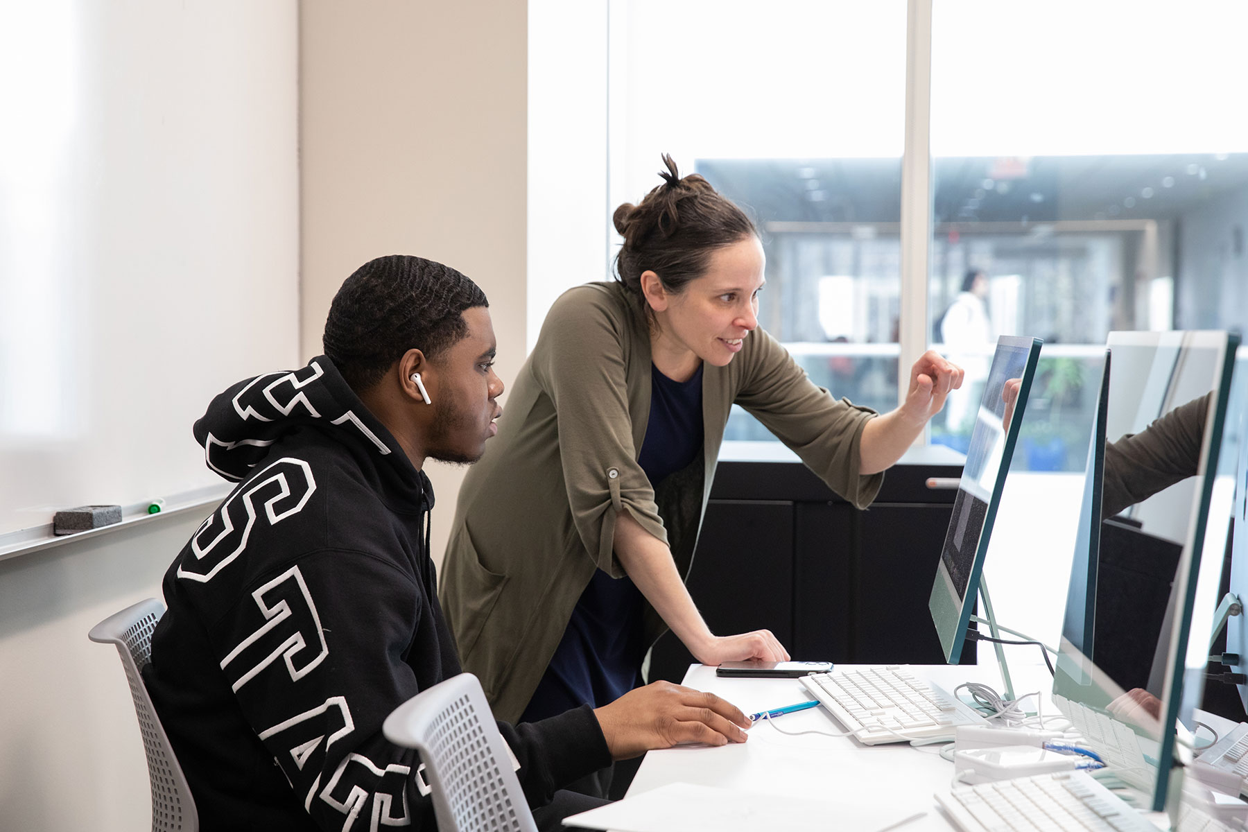 UM-Dearborn professor pointing to a computer screen with a student in a CASL classroom.