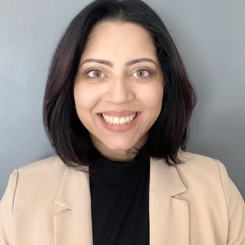 Individual headshot in a black blouse with a beige blazer.