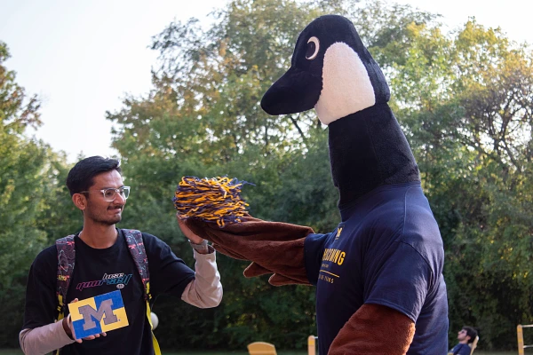 Bruce the goose and a student high fiving