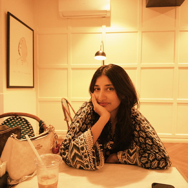 Person with long hair and sweater smiling at a desk.