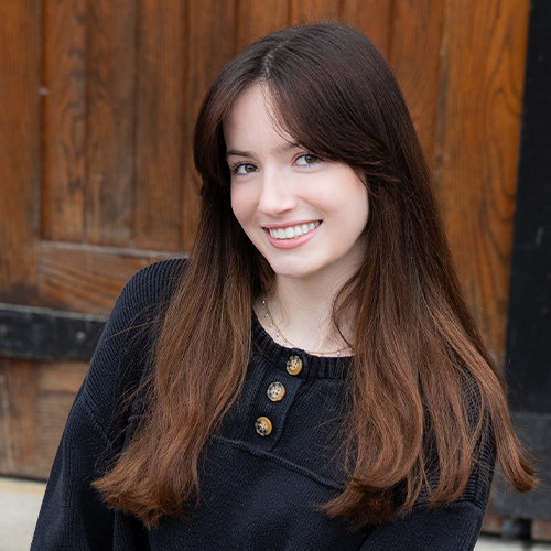 Person smiling at the camera with long hair in a black shirt.