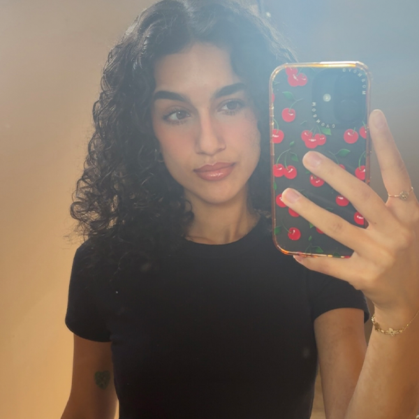 Person with long curly hair wearing a t-shirt taking a selfie.