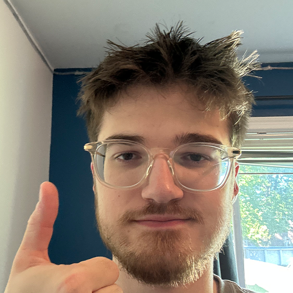 Person with short hair and glasses taking a selfie with a thumbs up.