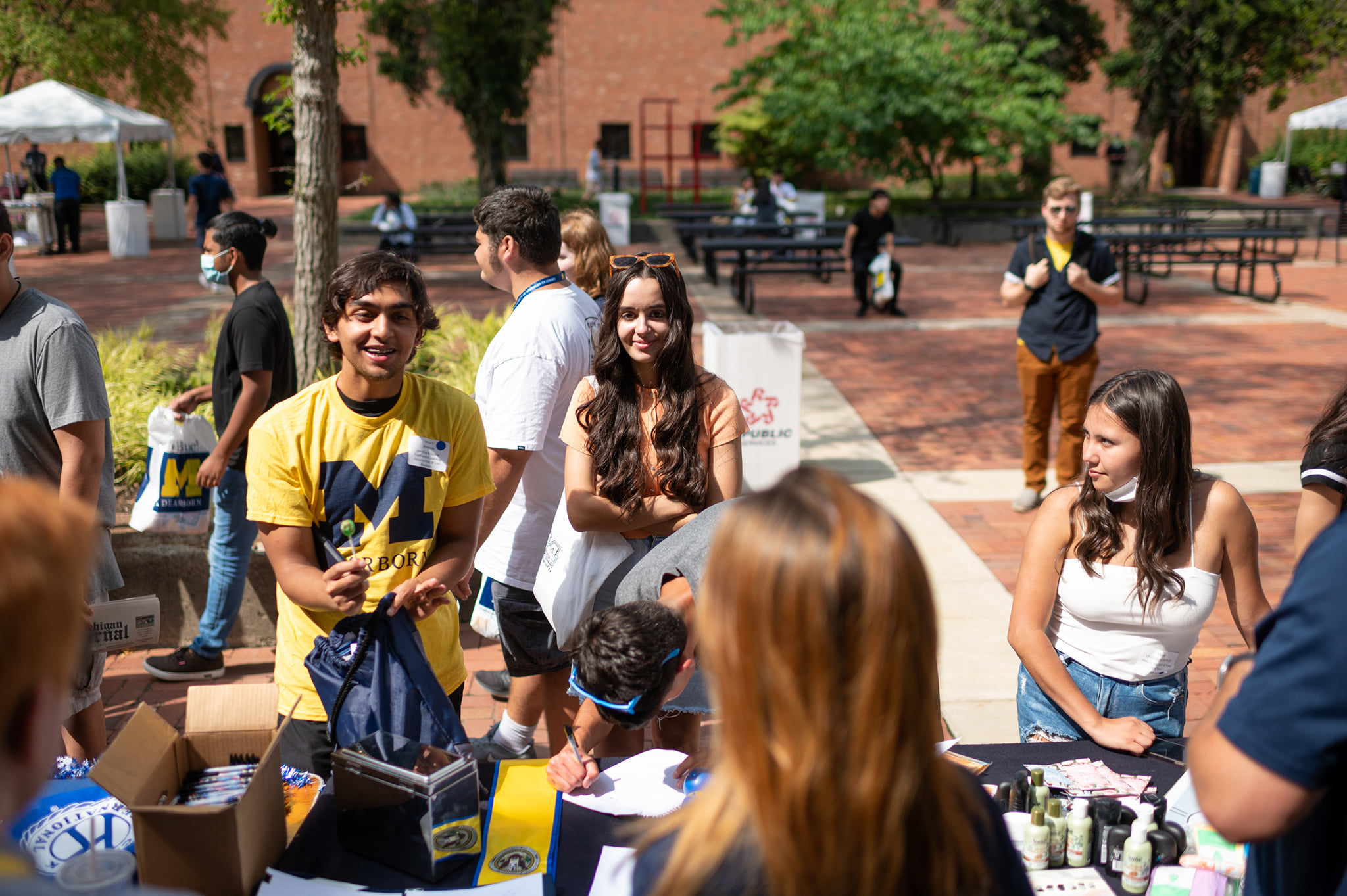 Smiling students line up to get swag at a welcome back to campus event on a sunny day in September.