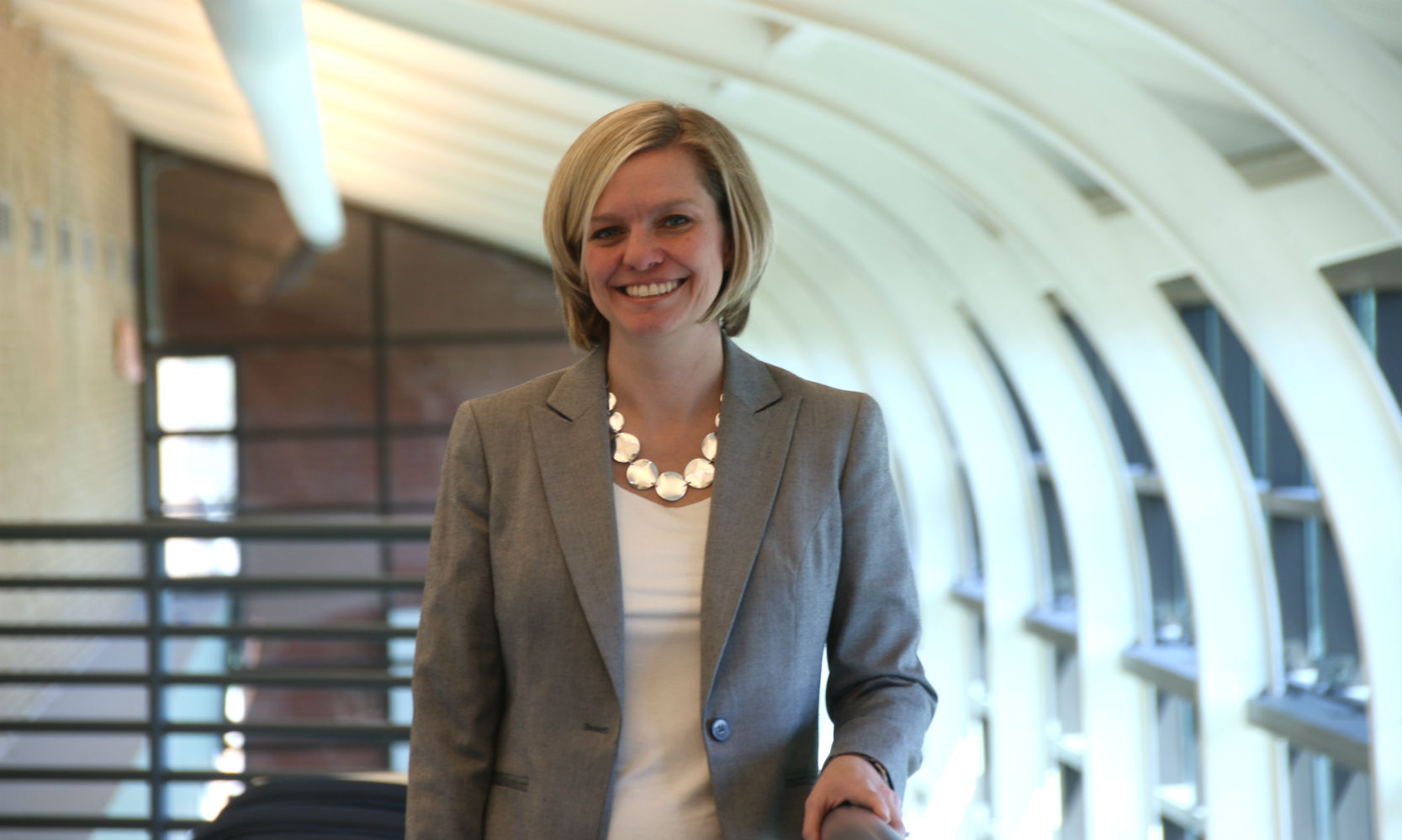 Amy Finley is a middle-aged white woman with blue eyes and chin-length blonde hair. She is wearing a gray blazer with a white v-neck blouse underneath and a chunky silver necklace.