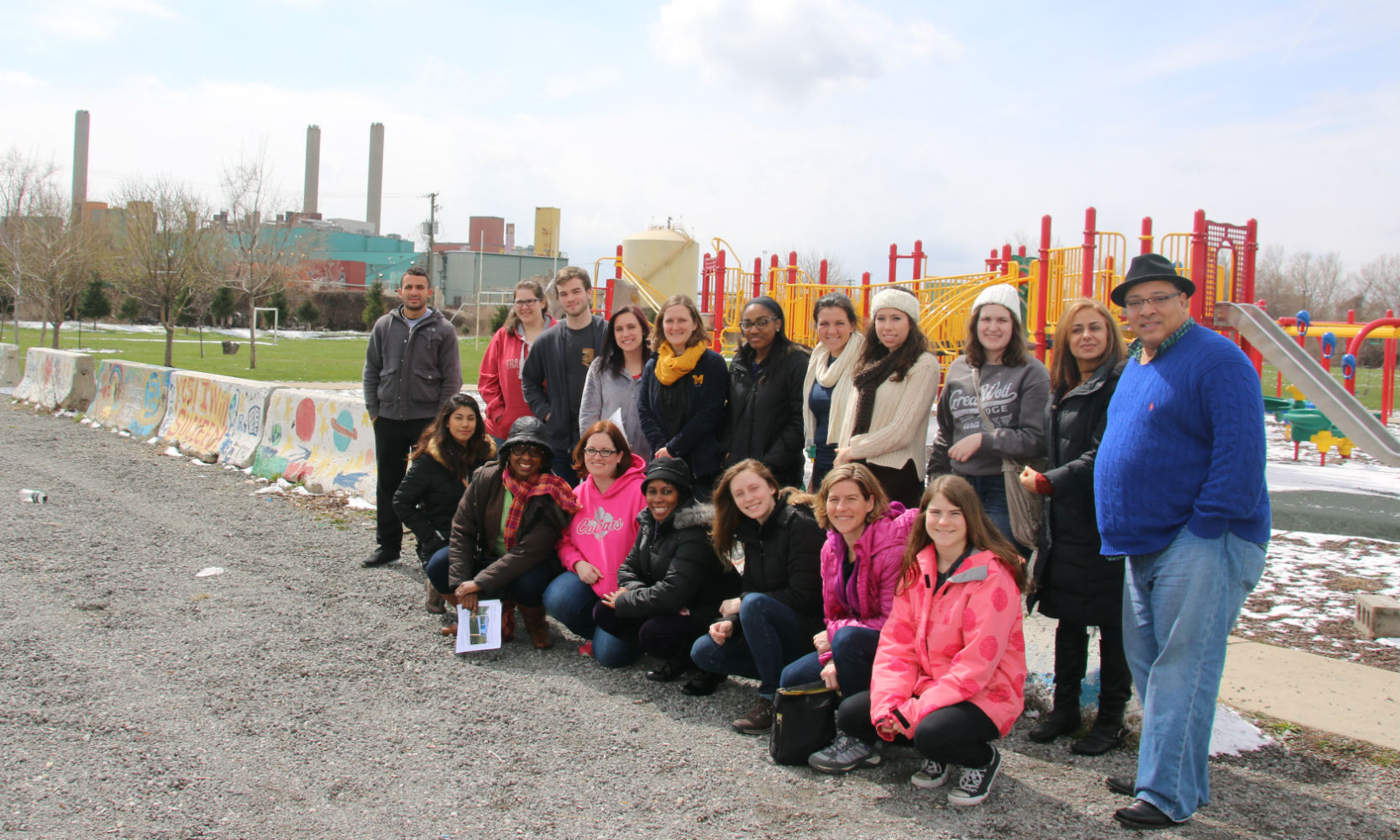 A group of young student volunteers stand outside of a red and yellow playground in Detroit’s Delray neighborhood during the Environmental Justice Tour of Detroit.