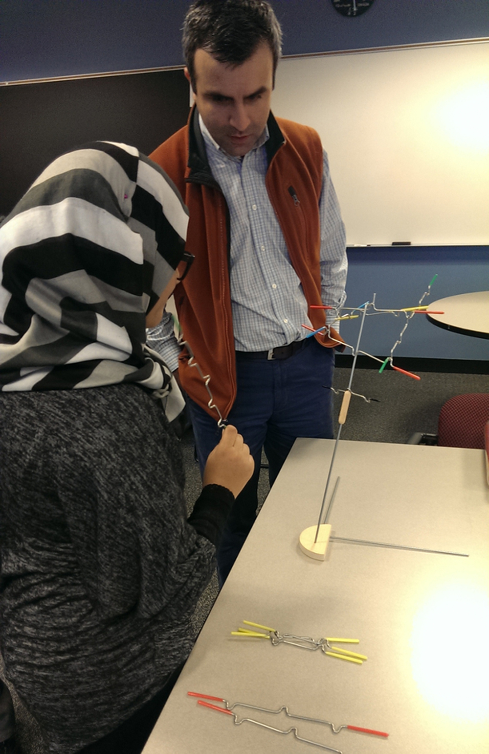 Instructor watching woman in hijab build a structure as part of Math Circles program