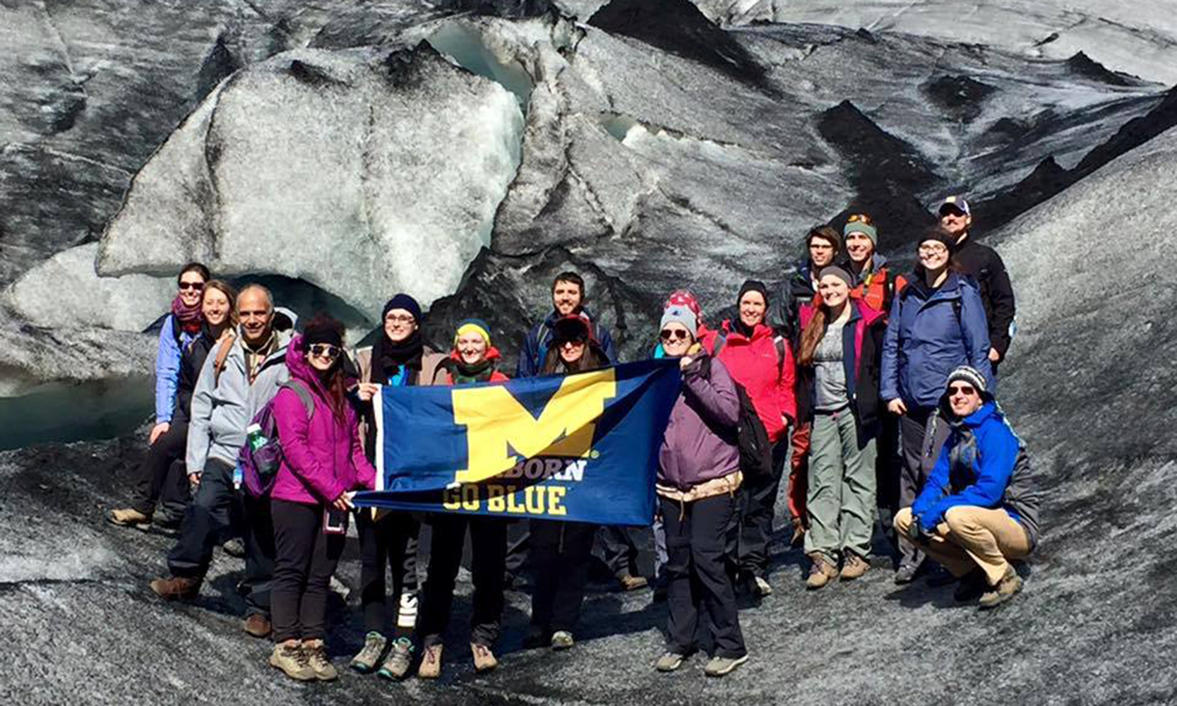 Students holding UM-Dearborn Go Blue flag in Iceland