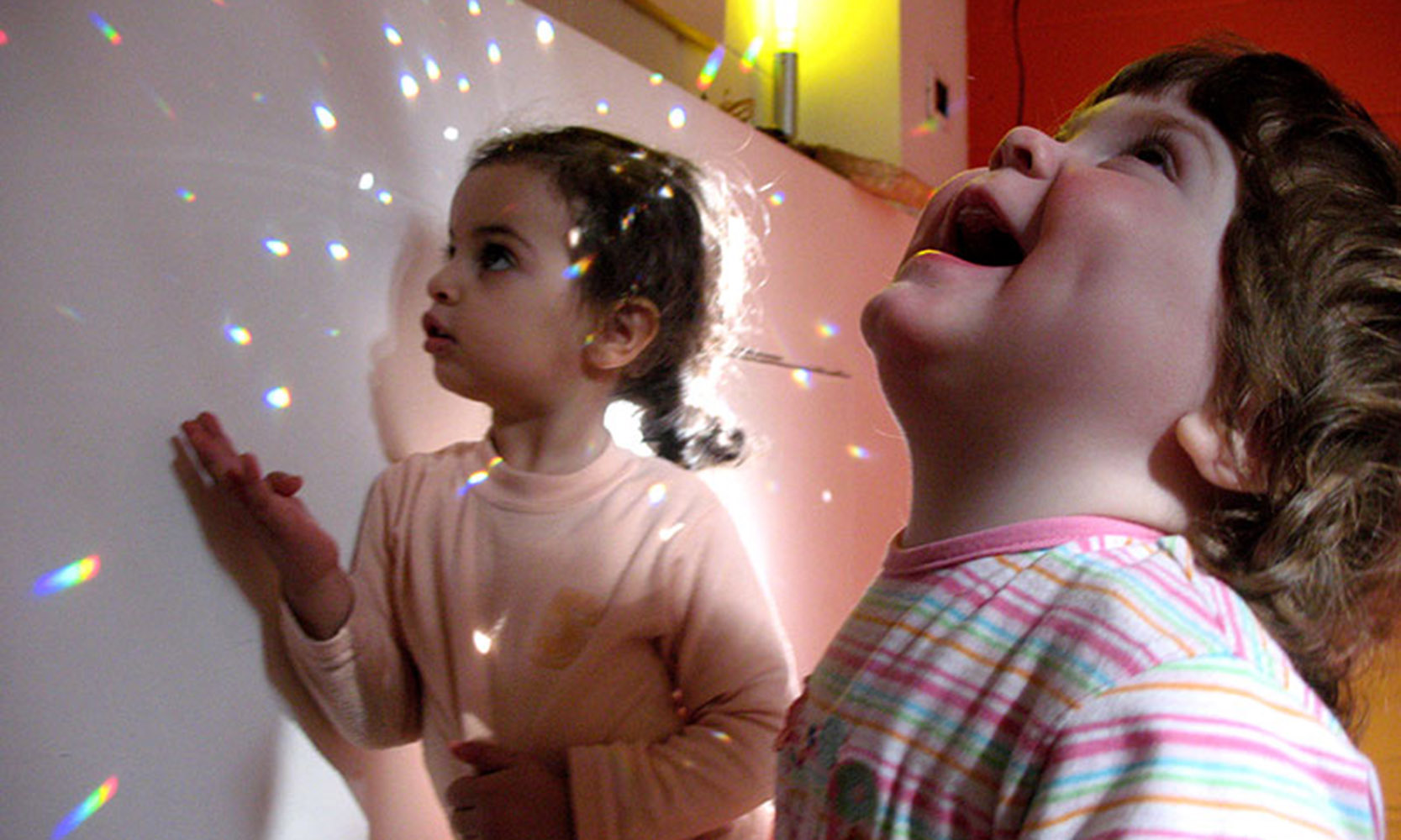 2 children looking at lights projected on the walls.